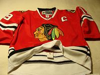 Front of red Chicago Blackhawks jersey with Native American logo, captain 'C' patch, and number 19 on sleeve.