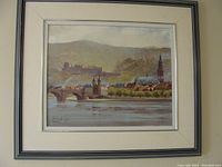 Framed oil painting showing a European riverside cityscape with historic buildings and a bridge, signed by artist Karl Arntz.