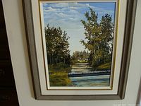 Full view of the framed oil painting showing the landscape scene with bridge and trees.