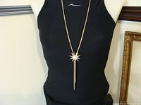 Full view of the starburst rhinestone necklace worn on a black mannequin to show size and design.
