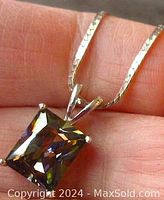 Close-up of rectangular mystic topaz pendant held in hand showing stone colors and silver setting