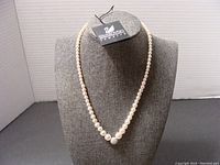 Full view of the 16" pearl necklace on grey bust with Swarovski tag