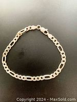 Full view of vintage sterling silver Figaro bracelet arranged on dark surface showing chain links and clasp.