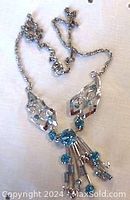 Photo of full length of vintage sterling silver necklace with aqua blue rhinestones laid flat showing clasp and chain details.
