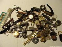 Top view of assorted vintage watch lot showing various metal and leather bands, watch faces, and parts spread on surface.