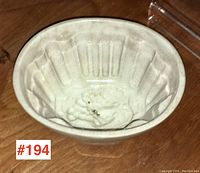 Top angle inside view showing the oval shape, scalloped vertical ridges, and flower/fruit decoration in center bottom of ceramic blancmange mould.