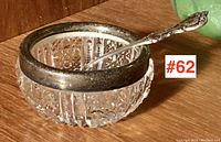 Close-up of the cut crystal salt cellar with a tarnished sterling silver rim and the sterling salt spoon placed inside.