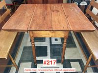Antique pine drop leaf table shown from the side with drop leaves down, displaying turned legs and pine benches beside it.