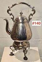 Full view of teapot on stand showing overall form and engraving