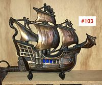 Front view of copper plated cast iron ship lamp with sails and blue glass windows.