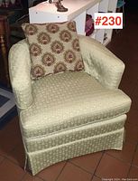Front view of vintage tub chair with patterned accent pillow, showing the light green circular patterned upholstery and skirted base.