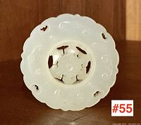 Front view of circular white jade disc showing carved scroll motifs and central wheel
