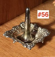 Front angled view of the sterling silver ring stand showing ornate decorative edges and central cone for rings.