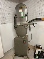 Full front view of the gray metal bandsaw mounted on stand with caster base