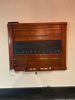 Full front view of the wood scoreboard showing numbers and chalkboard area with chalk writing; includes white chalk and black eraser on top.
