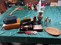 Wide shot of entire lot on green tablecloth showing boxes, figurines, vase, and bar tray