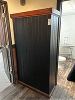 Front and right-side view of black-painted cupboard showing exterior finish and overall dimensions.