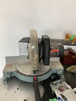 Front view of the Delta mitre saw showing blade, blade guard, motor, and base with angle scale.