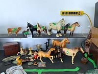 Overview of entire collection including porcelain animal figurines, carved wood figure, wooden chest, plastic tiger and assorted small items.