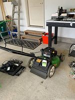 Angled front view of mower in garage showing overall assembly and attached rear bagger.