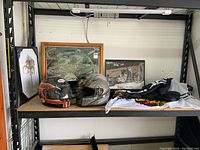 Overview of shelf with four racing helmets, framed pictures behind them, and Porsche flags on the side