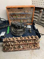 Black and Decker rotary tool placed on a tray next to one wooden rack of multiple rotary accessory bits with various shapes and sizes.