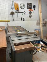 Front left three-quarter view of table saw showing cast iron top, fence assembly, open front drawer and lower base.