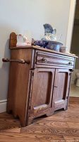 Front view of wood wash stand showing drawer, panelled doors, towel rod