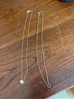 Two gold necklaces displayed flat on wooden surface
