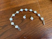 Full set photo showing freshwater pearl bracelet with linked pearls and matching stud earrings arranged on wooden surface.