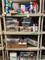Four shelves holding various household cleaning supplies including Swiffer pads, spray cleaners, storage containers, and a boxed Black and Decker jigsaw.