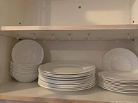 Wide shot of stacked bowls, dinner plates, and side plates with visible textured rim pattern