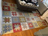 Full view of large geometric patterned wool area rug on hardwood floor extending from behind a couch.