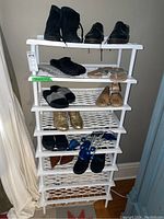 Full view of white plastic shoe rack filled with various women's shoes including boots, dress shoes, sandals, and loafers.