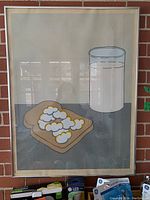 Frontal view of framed print leaning against brick wall showing entire artwork and frame