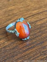 Top view of sterling silver ring with oval carnelian stone and ornate silver prongs.