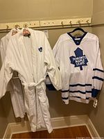 Photo of Toronto Maple Leafs NHL jersey and two white bathrobes hanging on hooks.