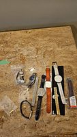 Overview of watches and assorted extra straps and links on a stone surface