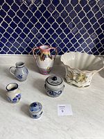 Full view of six items: salt glaze jars and small creamers, glazed ceramic vase, decorative planter