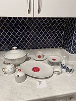 Overall lot contents featuring soup tureen, sugar pots, platter, lunch plates, and vases arranged on counter