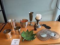 Full view of the assortment showing candleholder with candle, brass figurine, leaf dish, decorative mirrors, and metal cups including silver plated and brushed finish.