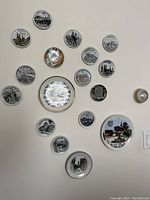 Photo showing 18 different collectible decorative plates arranged on a wall, featuring black and white and colored illustrations of German landmarks and towns.