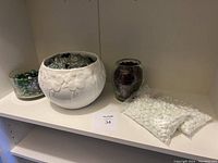 Shelf with three glass planters and multiple bags of white glass beads along with loose coloured beads.