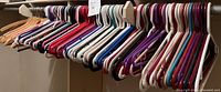 Photo showing assorted plastic clothes hangers in multiple colors on a metal hanging rod.