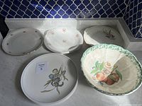 Group photo showing multiple decorative plates and large ceramic bowl on marble surface