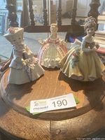 Photo showing all three vintage porcelain figurines on wooden surface, including the Lefton Miss Dainty and two other woman in dress figures.