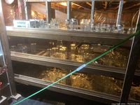 Three level shelf with numerous clear glass canning jars of various sizes arranged on shelves