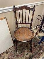 Dark wood antique chair with turned spindles and round seat showing wear
