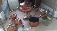 Full view of lot showing all copper items arranged on a table next to a window.