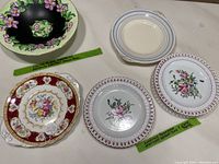 Top-down view of five dessert plates arranged with visible floral majolica patterns and Luneville-style designs.